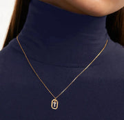 A gold initial pendant featuring a shiny letter charm on a delicate gold chain, adding a personalized and elegant touch to any outfit.